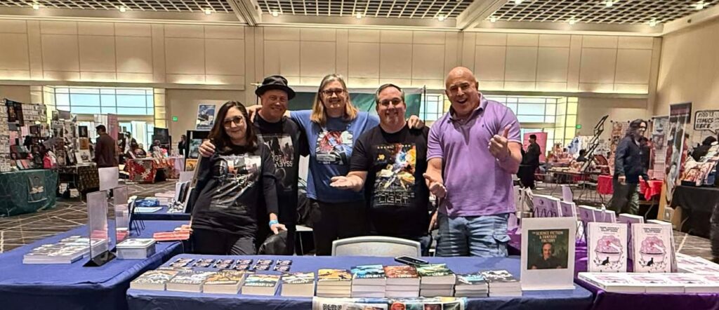 Five authors at a table surrounded by books
